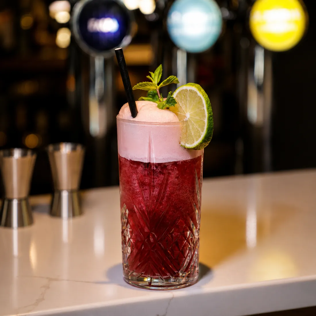 Cocktail aux fruits rouges et mousse rosée sur le comptoir du bar